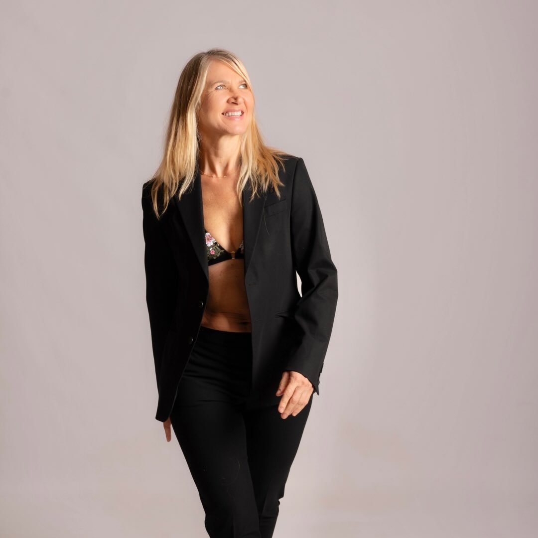 Stylish woman in black suit and floral bikini top posing in studio